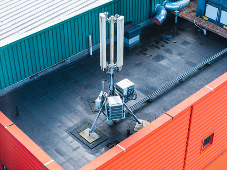 Aerial view of a cellular base station antenna mounted on a flat rooftop with orange and green metal walls in Riga Latvia. Aerial view of a cellular base station antenna mounted on a flat rooftop with orange and green metal walls in Riga Latvia.