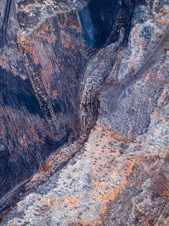 Aerial view of an open pit mine showcasing layered rock formations and mineral deposits in the rugged terrain of Iceland. Aerial view of an open pit mine showcasing layered rock formations and mineral deposits in the rugged terrain of Iceland.