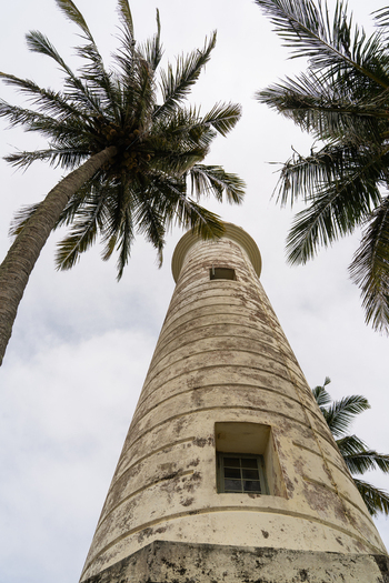 View of the historic Galle Lighthouse framed by tall palm trees under a cloudy sky in Galle Southern Province Sri Lanka.