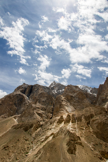 View of K2 Base Camp surrounded by rugged rocky mountain peaks under a bright blue sky with scattered white clouds Gilgit Baltistan Pakistan. View of K2 Base Camp surrounded by rugged rocky mountain peaks under a bright blue sky with scattered white clouds Gilgit Baltistan Pakistan.