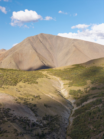 Aerial view of San Luis Peak with its rugged slopes rocky terrain and green alpine vegetation under a bright blue sky in Gunnison Colorado United States.