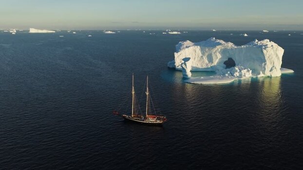 Aerial view of sailboat near arch iceberg Greenland. Aerial view of sailboat near arch iceberg Greenland.