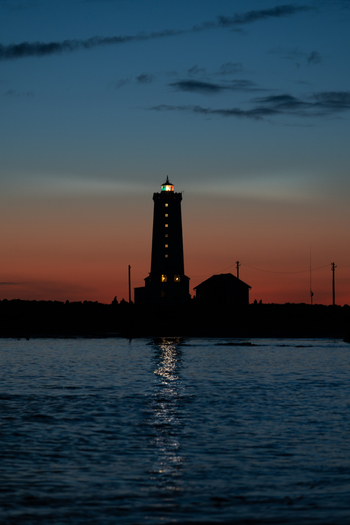 View of Grotta Lighthouse silhouetted against a vibrant sunset sky with glowing windows and water reflections Seltjarnarnes Seltjarnarnesbaer Iceland. View of Grotta Lighthouse silhouetted against a vibrant sunset sky with glowing windows and water reflections Seltjarnarnes Seltjarnarnesbaer Iceland.