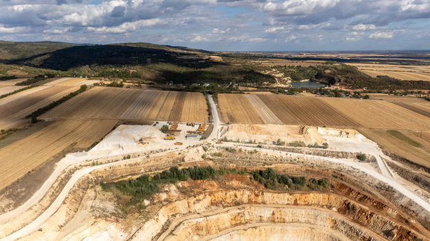 Aerial view of the open pit quarry in Besenovo surrounded by agricultural fields and rolling hills under a cloudy sky in Vojvodina Serbia. Aerial view of the open pit quarry in Besenovo surrounded by agricultural fields and rolling hills under a cloudy sky in Vojvodina Serbia.
