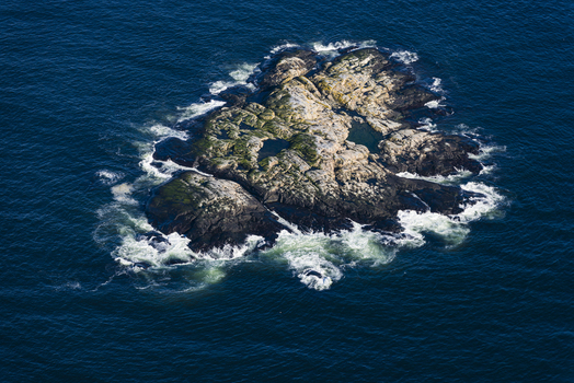 Aerial view of the rocky skerry Pater Noster Skaren surrounded by deep blue sea with white waves crashing against the shore in Kladesholmen Vastra Gotalands lan Sweden.