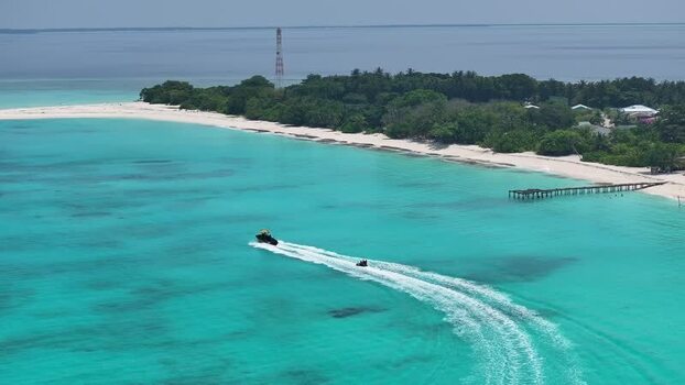 Aerial view of a boat towing an inflatable tube near the beach in Maldives. Aerial view of a boat towing an inflatable tube near the beach in Maldives.