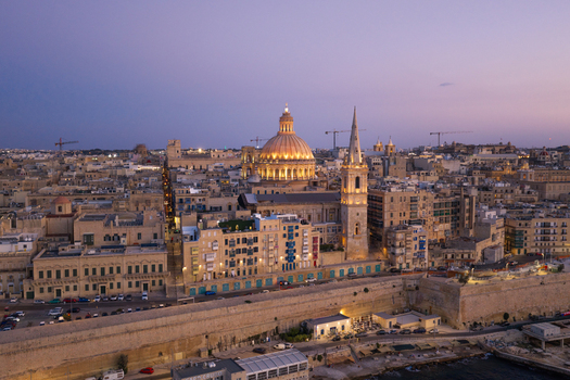 Aerial view of the historic skyline of Valletta featuring the illuminated dome of the Basilica of Our Lady of Mount Carmel and the spire of St. Paul s Pro Cathedral at dusk in Valletta Port Region Malta. Aerial view of the historic skyline of Valletta featuring the illuminated dome of the Basilica of Our Lady of Mount Carmel and the spire of St. Paul s Pro Cathedral at dusk in Valletta Port Region Malta.