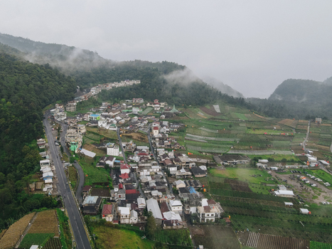 Aerial view of a hillside village with terraced fields and a winding road nestled among misty mountains in Tawangmangu Central Java Indonesia.