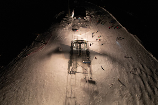 Aerial view of Les Crosets ski resort at night with an illuminated chairlift station and skiers on the snow in Val d Illiez Valais Switzerland. Aerial view of Les Crosets ski resort at night with an illuminated chairlift station and skiers on the snow in Val d Illiez Valais Switzerland.