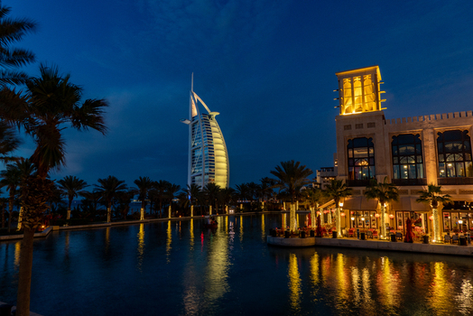 View of the illuminated Burj Al Arab hotel and traditional wind towers reflecting in the water canal at night in Dubai Dubai United Arab Emirates. View of the illuminated Burj Al Arab hotel and traditional wind towers reflecting in the water canal at night in Dubai Dubai United Arab Emirates.