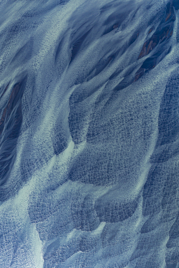 Aerial view of intricate braided glacial river patterns with blue water and textured sediment in Hofn Sveitarfelagid Hornaf Iceland.