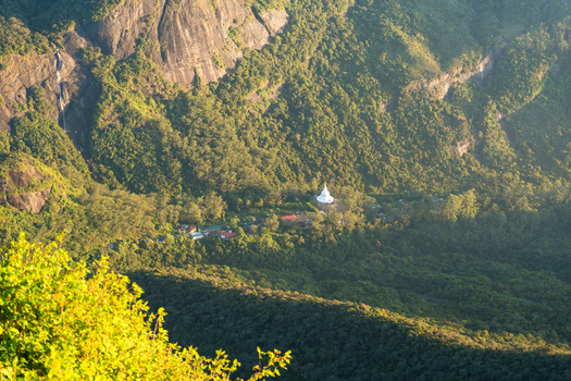 View of the white Peace Pagoda nestled in the lush green valley of Adam s Peak surrounded by steep rocky cliffs and dense forest in Ratnapura Sabaragamuwa Province Sri Lanka. View of the white Peace Pagoda nestled in the lush green valley of Adam s Peak surrounded by steep rocky cliffs and dense forest in Ratnapura Sabaragamuwa Province Sri Lanka.