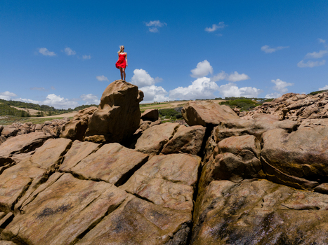 Aerial view of a woman in a red dress standing on a rock at Injidup Natural Spa surrounded by rugged coastal landscape in Yallingup Western Australia Australia. Aerial view of a woman in a red dress standing on a rock at Injidup Natural Spa surrounded by rugged coastal landscape in Yallingup Western Australia Australia.