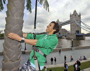 Dame Kelly Holmes climbs up a 23ft coconut tree at the Vita Coco Coconut Grove in Potters Fields London