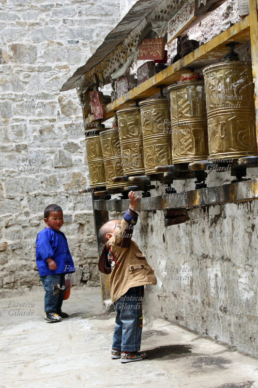 TIBET Nel Monastero di sera, nei pressi di Lhasa, un bimbo si allunga per girare le ruote di preghiera buddiste -maggio 2009