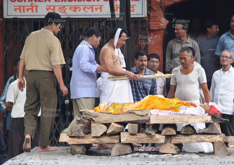 NEPAL Pashupatinath, cerimonia induista di cremazione sulla riva del sacro fiume Bagmati . Il corpo del defunto posa sulla pira di legna, mentre il figlio maggiore compie i dolorosi riti che precedono l\