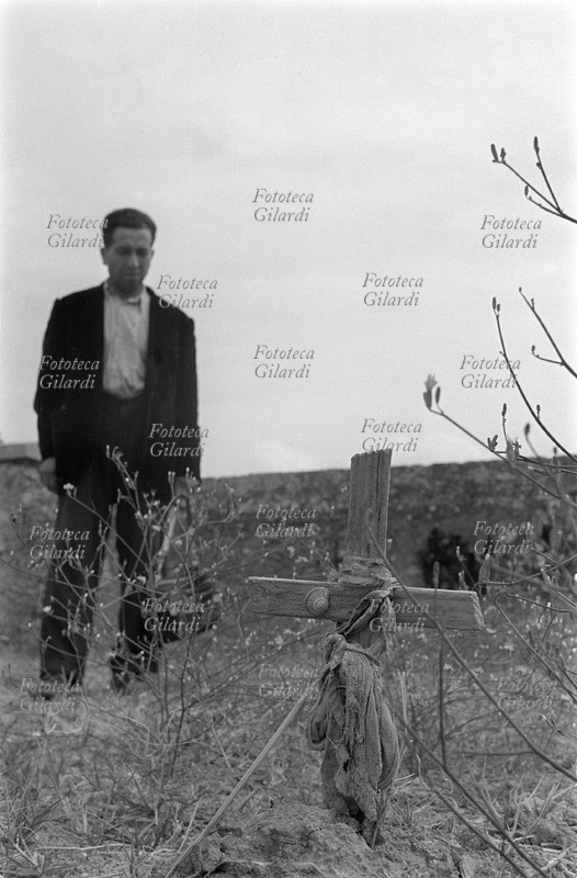 ECCIDIO DI MELISSA 29 ottobre 1949. Visita al cimitero di Melissa (Crotone) a 5 anni dalla carneficina: una delle modeste croci di legno poste sulle tombe dei braccianti uccisi. Una figura umana appare in secondo piano, sfocata, accentuando la nitidezza e l\