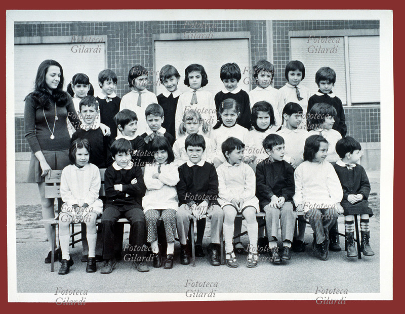 SCUOLA Scolaresca mista di una seconda classe elementare posa per la foto di gruppo Le femmine indossano il grembiule bianco, i maschi il grembiule nero Alcuni dei bambini sono distratti dall\