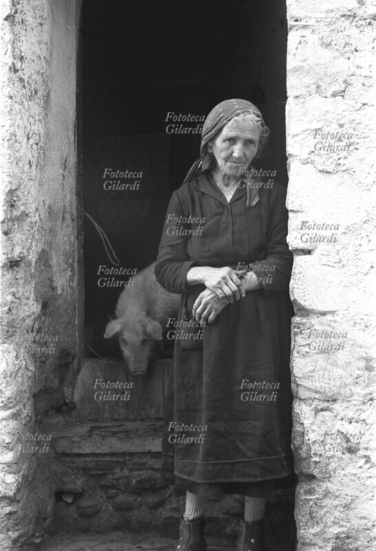 LUCANIA Donna anziana ritratta davanti alla porta della sua abitazione (dietro a lei un maialino), vittima del malocchio fattole da persone nemiche. Immagine a documentazione dell\