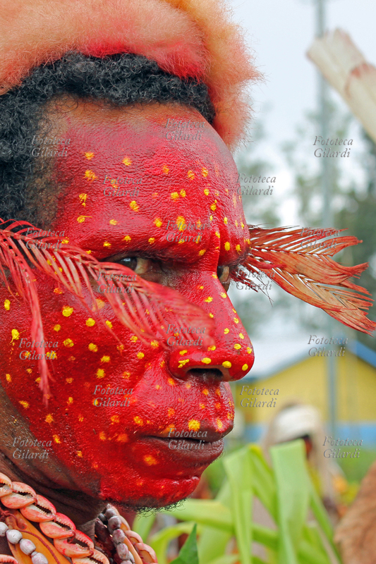 OCEANIA Uomo della tribù Foi, che vive nella area del Lago Kutubu, dipinto in viso con i colori tradizionali: il rosso, per gli uomini adulti. Indossa il costume tribale per il festival di "Sing Sing", che dal 1961 riunisce ogni anno a Mount Hagen migliaia di guerrieri e partecipanti vari di tutte le tribù della regione, che celebrano e consolidano la convivenza pacifica esibendosi in competizione nelle proprie danze accompagnate da musiche e canti tribali, per due giorni, nei costumi tradizionali, con il volto e il corpo dipinti nei colori rituali. Fotografia di Raffaella Milandri, Mount Hagen, Papua Nuova Guinea, 17 agosto 2013