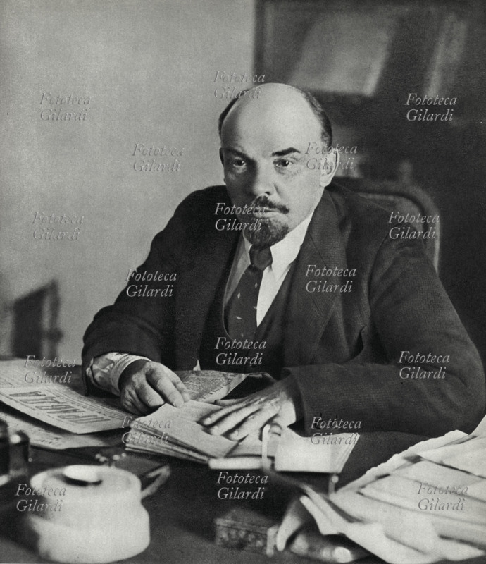 Vladimir Ilic LENIN (1870-1924) ritratto fotografico alla scrivania, sulla quale legge un libro e una copia della Pravda. Mosca, 1918