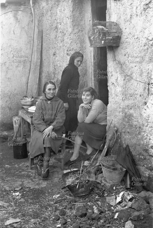 FAMIGLIA donne dei sobborghi romani ritratte sulla soglia della loro abitazione. Sullo sfondo una donna vestita di nero entra in casa. Un\