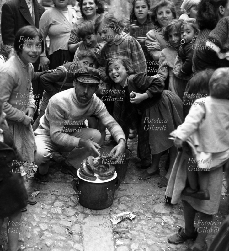 BAMBINI e giovani madri raccolti festosamente intorno a un venditore di polpo cotto. Fotografia di Ando Gilardi (1921 - 2012) #andogilardi, Palermo 1955 circa.