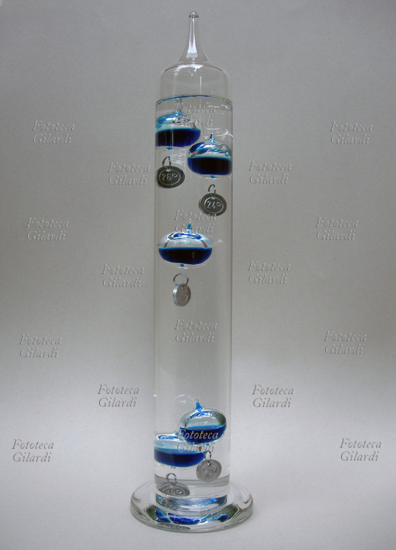TERMOMETRO galileiano, un tubo di vetro saldato riempito con acqua in cui sono immerse alcune ampolle di vetro riempite con una miscela liquida colorata (alcol o acqua con colorante). Ogni ampolla ha attaccata una leggera targhetta metallica che indica numericamente una temperatura. Il peso di ciascuna targhetta è accuratamente calibrato e differente l\