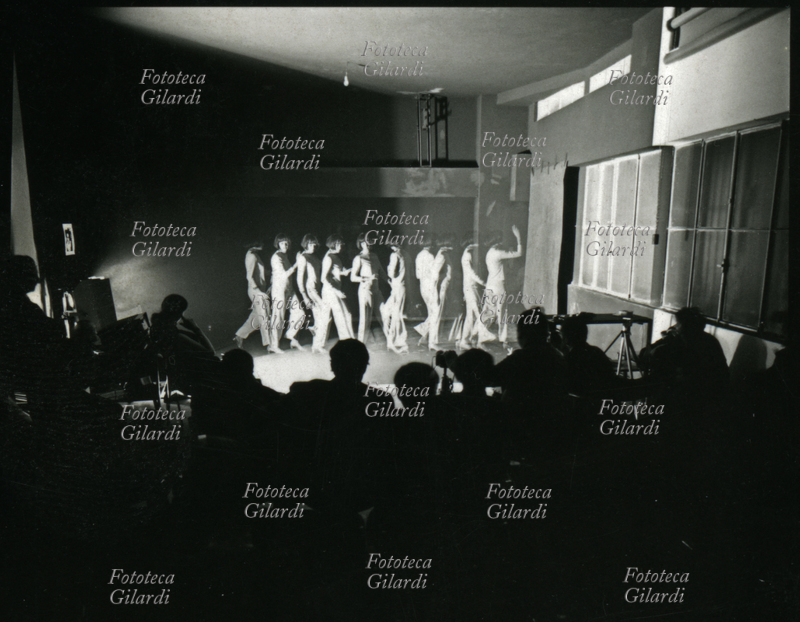 PHOTOGRAPHY multiple exposure on the same frame made with a stroboscopic flashing light: a girl steps forward from the left and raises one arm; moment of a lesson by Ando Gilardi (1921 - 2012) #andogilardi on the theme "black and photography". Milan, 1970