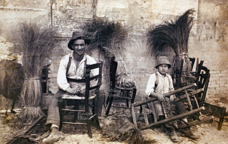 MESTIERI Impagliatori e riparatori di sedie impagliate, padre e giovane figlio ritratti nello svolgimento del loro lavoro. Fotografia degli ultimi anni del XIX secolo