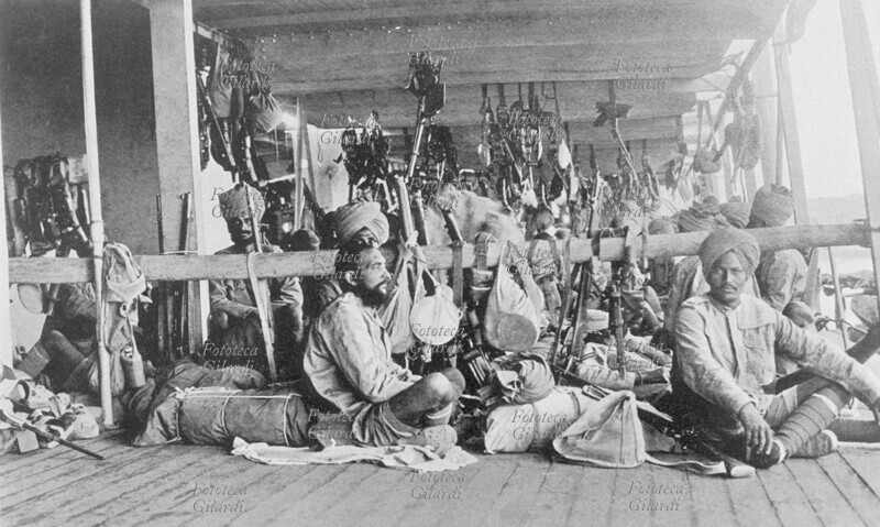 I GUERRA MONDIALE Truppe indiane impiegate dagli inglesi nella campagna in Mesopotamia, fotografate in un momento di riposo. I soldati sono seduti in un porticato in legno, che aveva la funzione di deposito di armi e di munizioni. Mesopotamia, 1916