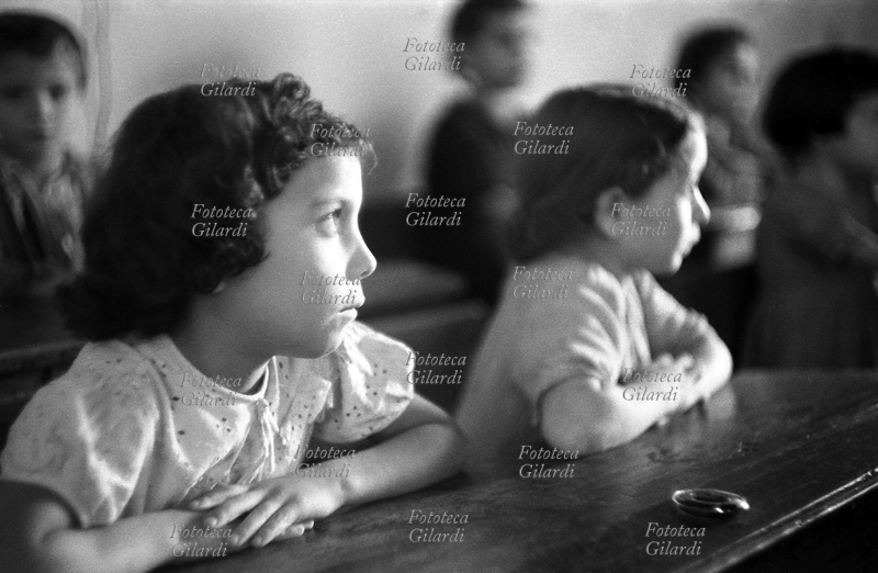 SCUOLA bambina in classe, segue la lezione dal suo banco. Fotografia di Ando Gilardi (1921 - 2012) #andogilardi, Melissa (Crotone) 1954.