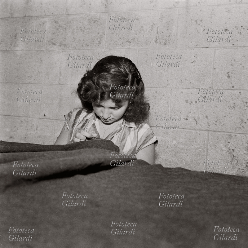 MESTIERI Lavoratrici tessili a domicilio: donna alla cucitura di un tessuto pesante; tempo permettendo, il lavoro veniva svolto all\