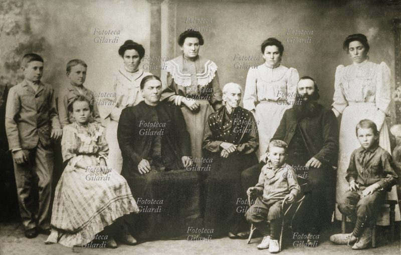 FAMIGLIA Gruppo matriarcale, quattro generazioni in posa per una fotografia ricordo dei primi anni del XX secolo. Al centro è seduta la nonna, la più anziana della famiglia; a lato il figlio con la moglie, davanti i bambini piccoli e in piedi, dietro al gruppo le figlie più grandi. Italia, 1905 circa