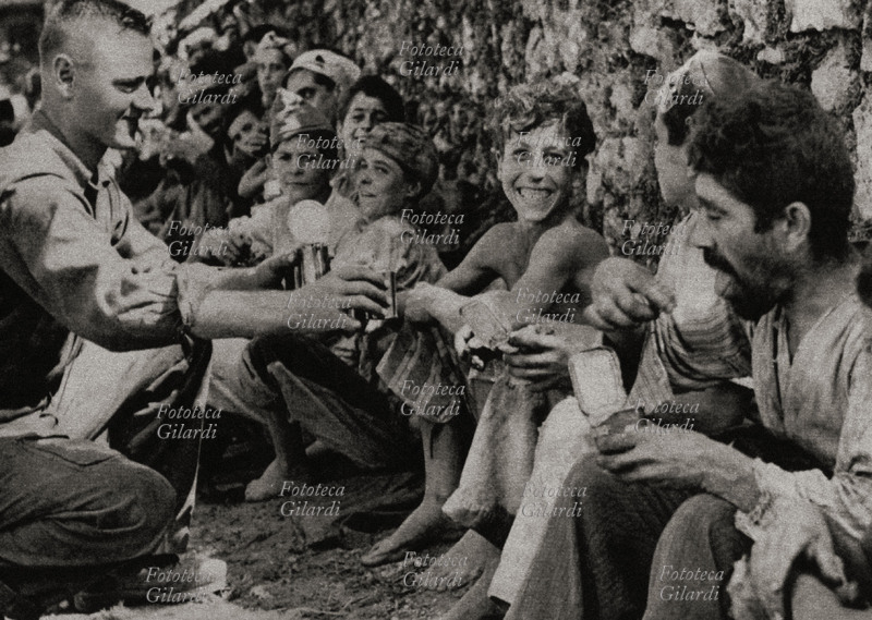 LIBERATION Southern Italy, an American soldier distributes cans to the starving population. Italy, September 1943.