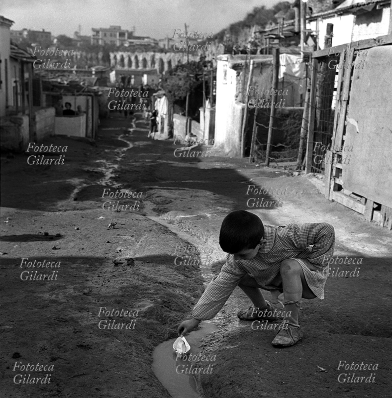 BAMBINI ragazzino gioca con una barchetta di carta in un rigagnolo d\