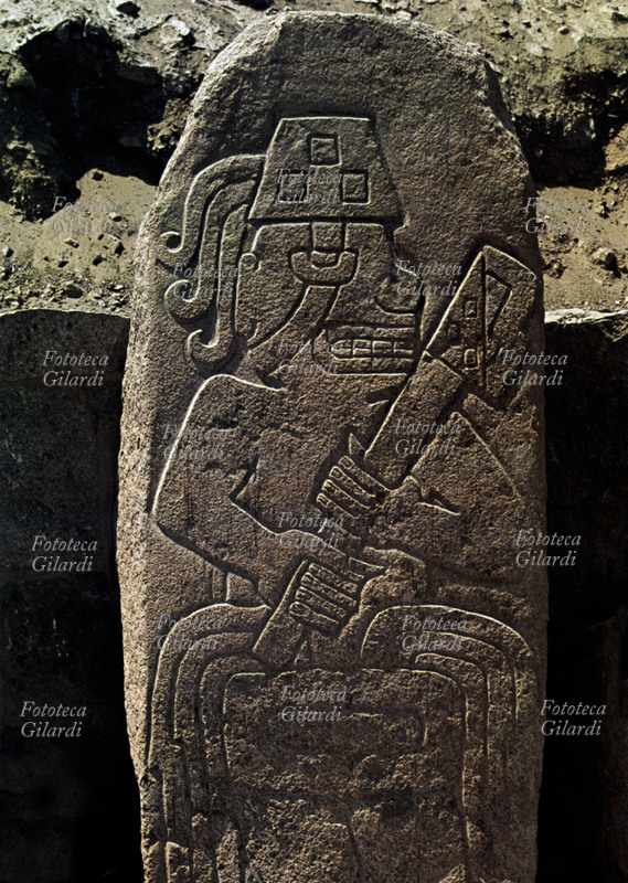 INCAS Cerro Sechin. Una delle numerose steli in pietra di calcare allineate e raffiguranti guerrieri in atteggiamenti minacciosi ed aggressivi, questo guerriero regge una scure nelle mani. Costa Nord, Valle Casma, Periodo Iniziale, 1800-900 a.C.