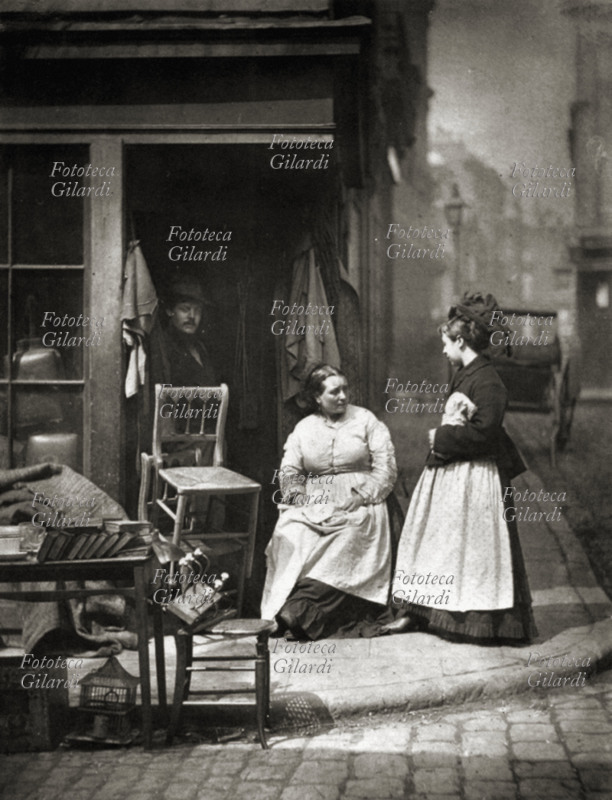 LONDRA Il negozio di mobili usati; una passante si ferma a parlare con la titolare seduta accanto alla merce esposta sul marciapiede, mentre il marito si affaccia all\