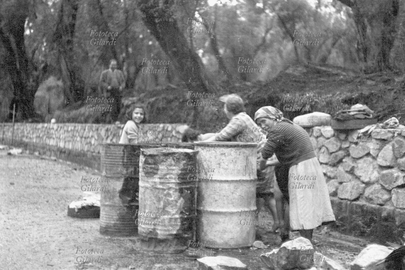 AGRICULTURE Seasonal Calabrian olive oil workers, who came from far away, were housed in wooden shacks in the olive grove during the three or four months of the harvest, without toilets, stoves, or running water. Here they washed in bins located near the road, where the water was renewed weekly. Photograph by Ando Gilardi (1921 - 2012) #andogilardi, part of the photo feature "Inchiesta tra gli ulivi" (Investigation Among the Olive Trees), published in installments as a summary of the study on the working conditions of olive pickers in Calabria, conducted in November 1957 by a commission of inquiry composed of CGIL trade unionists and association and parliamentary figures of various backgrounds, accompanied by a large series of images taken by the photographer. Published in "Lavoro," the trade union\