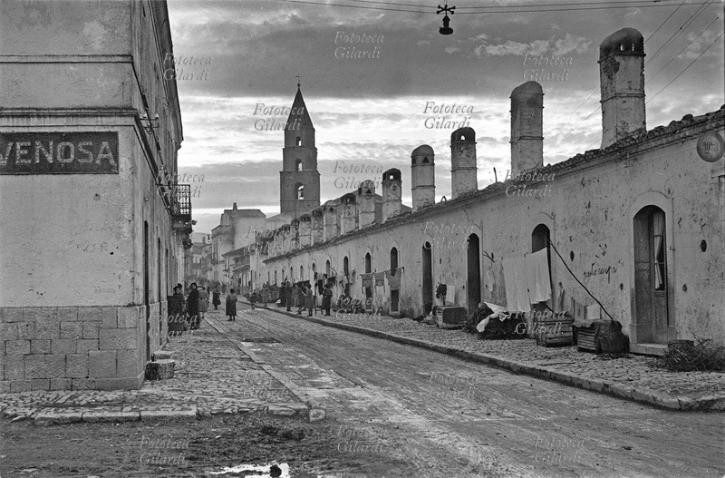 ITALIA Venosa, accesso da via Frusci, strada piena di fango con ingresso alle povere abitazioni dei braccianti. Fotografia di Ando Gilardi (1921-2012) #andogilardi, parte di un ampio servizio realizzato per \