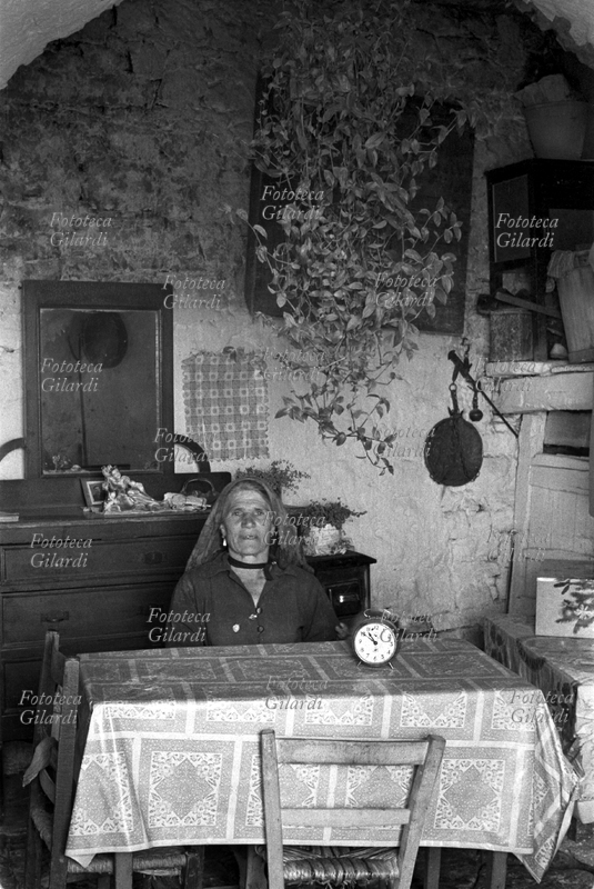 ALBANO DI LUCANIA Donna affatturata ritratta nella sua casa; da notare la rigogliosa pianta di miseria che è appesa sopra il tavolo. Immagine raccolta nel corso dell\