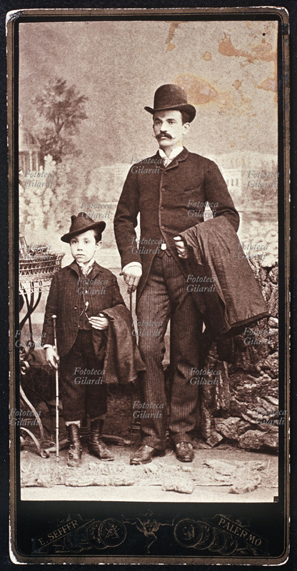 MODA Ritratto fotografico maschile raffigurante padre e figlio elegantissimi, il primo con bombetta ed il secondo con cappello floscio portato \