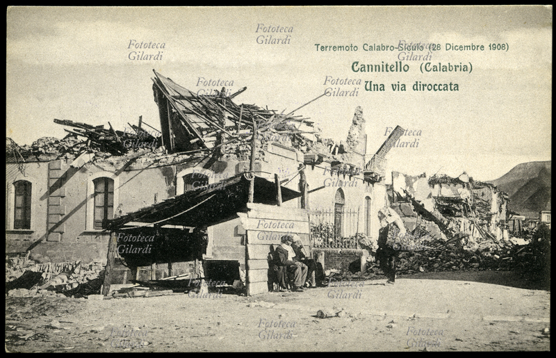 TERREMOTO Calabro-Siculo del 1908. Cannitello (Calabria) una via diroccata. Due anziani superstiti siedono sulla panca antistante un riparo di fortuna, tirato su alla meglio di fianco alle rovine dell\