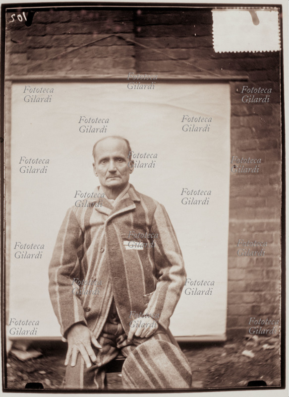 STORIA DELLA FOTOGRAFIA Ritratto segnaletico di Francesco Raglianti (omicida), eseguito con ausilio di sfondo bianco portatile; visione frontale in divisa da carcerato, col berretto appoggiato al ginocchio. Italia, 1907.