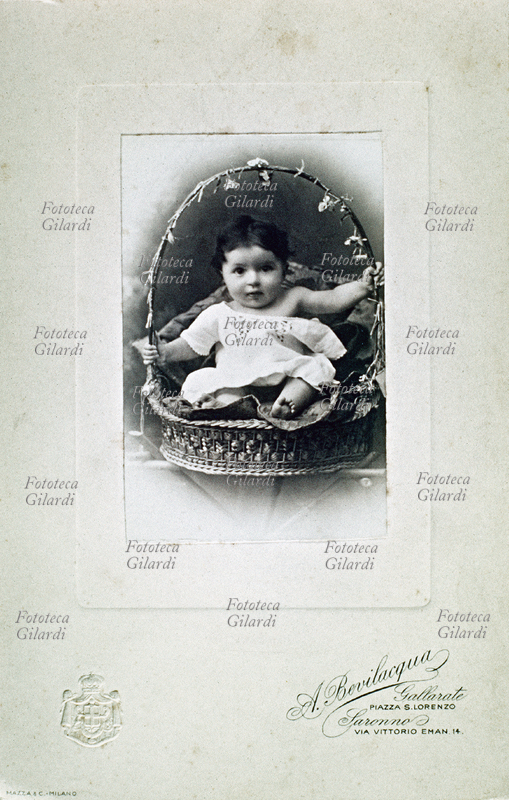 BAMBINI Fotografia ricordo. Bimbo di un anno in posa dentro un cestino. Fotografia A. Bevilacqua con marchio a secco di casa Savoia; Gallarate e Saronno, 1890 circa.