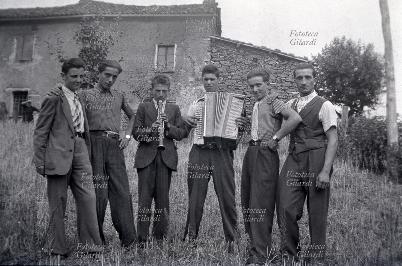 SUONATORI e cantanti per diletto; gruppo di sei ragazzi, età media 18 anni, che nei giorni di festa suonavano fisarmonica e clarinetto cantando canzoni popolari per amici e parenti. Il luogo è Caldasio: borgo dove si trova la casa natale del padre di Ando Gilardi, dove questi in seguito si rifugiò sfollato da Genova e si unì ai partigiani. È una delle prime fotografie scattate da Ando Gilardi (1921 - 2012). Ponzone (AL), 1936