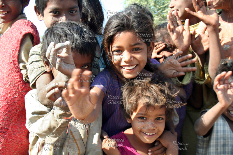 BAMBINI agitano le mani in segno di saluto festoso, alla periferia di Udaipur. Fotografia di Raffaella Milandri. India, Udaipur novembre 2007