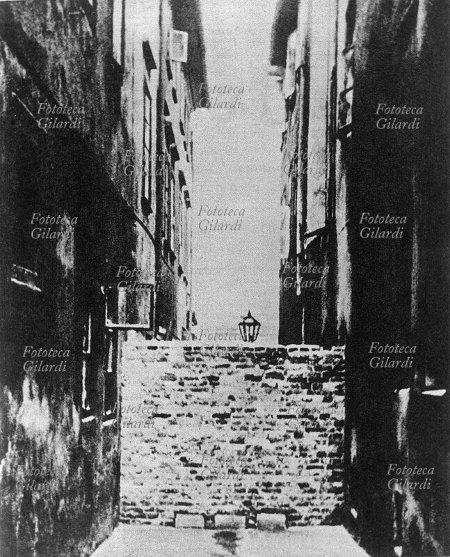 GHETTO DI VARSAVIA in Polonia, occupata dalla Germania nazista, viene decretato il concentramento degli ebrei nei ghetti: una strada della città che entra nel ghetto viene tagliata in due da un muro. I bambini ebrei uscivano ed entravano dai buchi in basso, praticati per lo scolo delle acque. Fotografia, Varsavia 1940