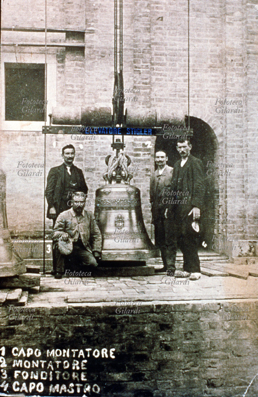 MESTIERI Italia, gruppo di fabbricanti di campane: 1- capo montatore, 2- montatore, 3- fonditore, 4- capo mastro, tutti in posa prima di innalzare la nuova campana sul campanile della chiesa di San Marco. Fotografia, Milano 1911.