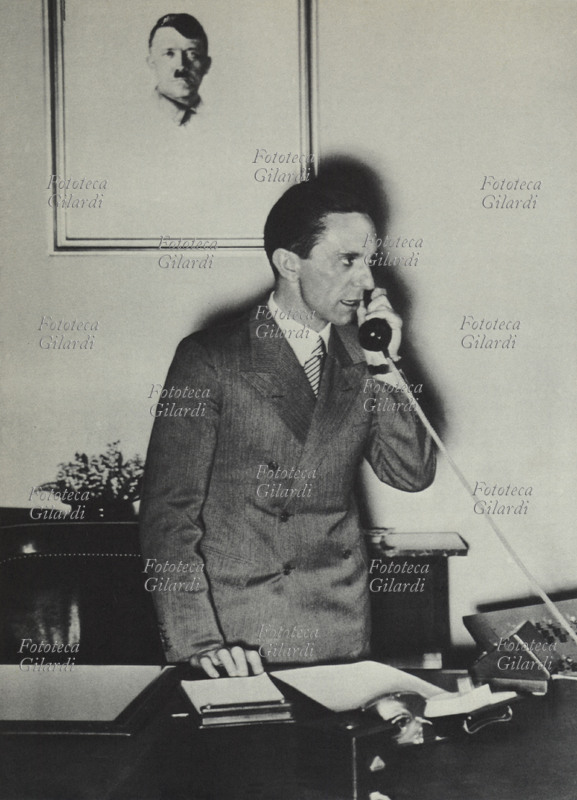 Joseph GOEBBELS (29 October 1897 – 1 May 1945) Minister of Propaganda and Information of National Socialism in Germany from 1933, on the telephone in his study. Behind him, a portrait of Hitler. Germany, 20th century.